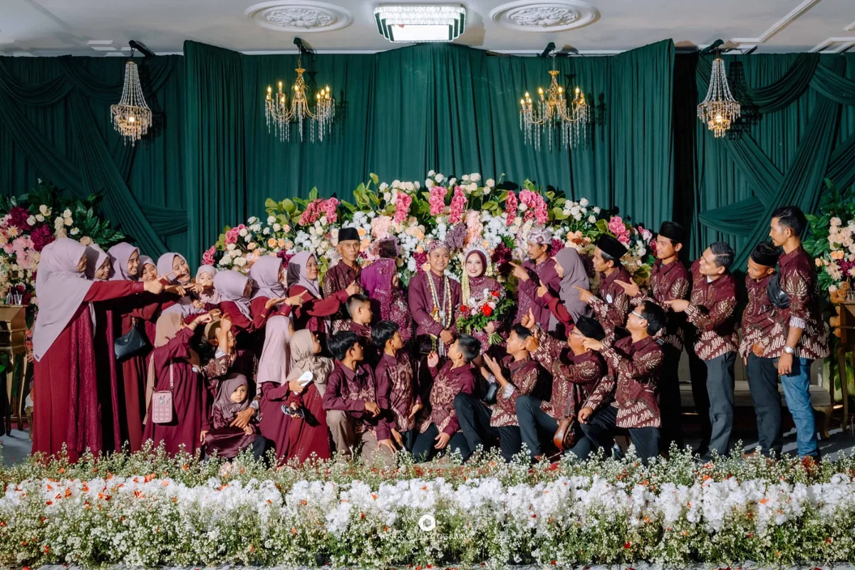 Puluhan tamu mengenakan batik seragam merah marun dalam satu resepsi