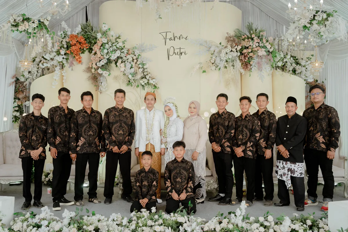 Keluarga besar mengenakan batik seragam coklat di pelaminan pernikahan