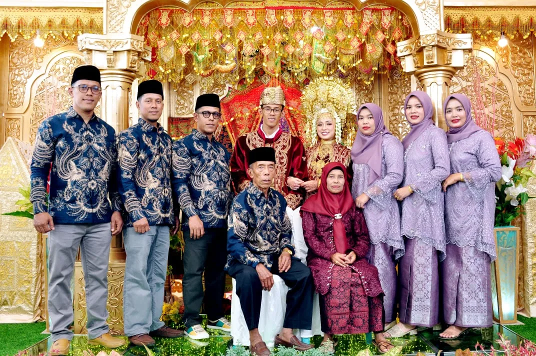 Rombongan keluarga berbatik senada berfoto bersama pengantin